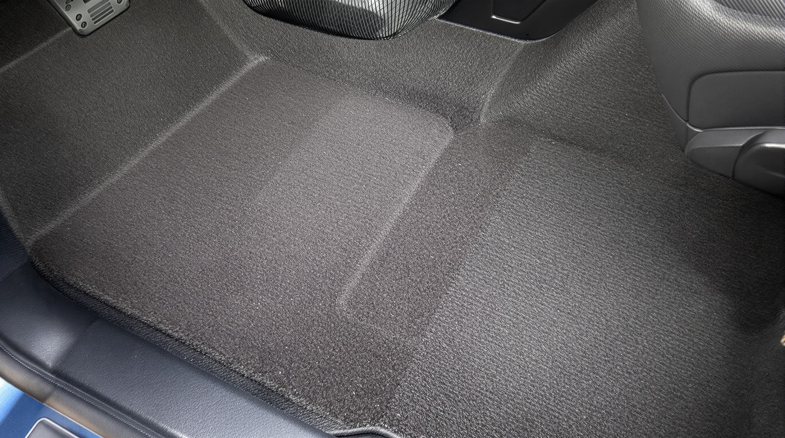 Deep plush dark car-floor carpet freshly cleaned and vacuumed in a tidy footwell